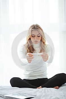 Girl looking at pregnancy test. Sad woman waiting pregnant test results