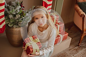 Girl looking on present near Christmas tree