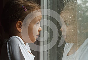 Girl looking at raindrops on the window