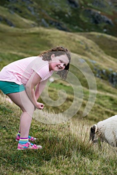 Girl looking at sheep grazing while walking up the Slieve League Cliffs, County Donegal, Ireland