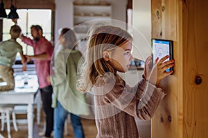 Girl looking at smart thermostat at home, checking heating temperature. Concept of sustainable, efficient, and smart
