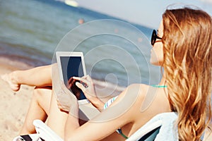 Girl looking at tablet pc on the beach