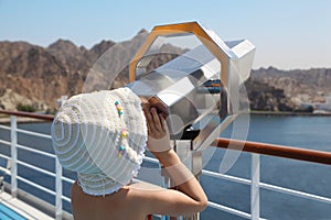 Girl is looking at telescope on deck of ship