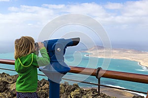 Girl looking through telescope at the island and the sea, Lanzarote