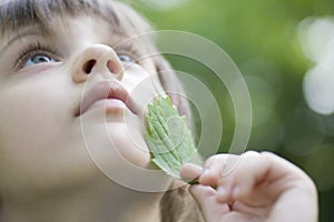 Girl Looking Up While Touching Leaf On Face