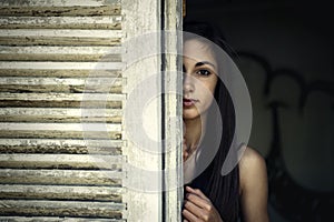 Girl looking through a window shutter photo