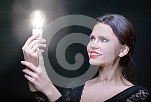 Girl looks with admiration at the burning bulb