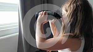 Girl looks in black binoculars optical instrument