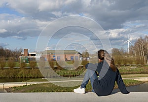 The girl looks into the distance. Heavenly landscape of storm clouds. Houses and energy windmill away