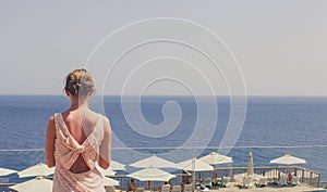 The girl looks into the distance on the sea on a warm summer day