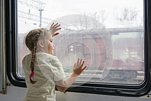 The girl looks into the distance from the window of a train car