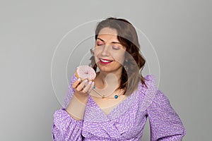 Girl looks at donut in purple dress on gray background