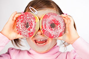 Girl looks through donuts