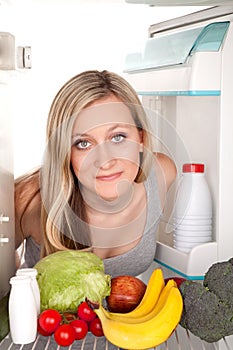 Girl looks inside refrigerator