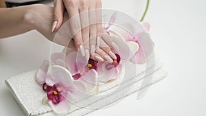 Girl looks at manicure on flower background