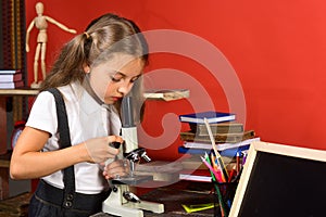 Girl looks into microscope, copy space. Science and study time