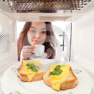 Girl looks in a microwave