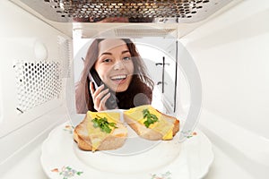 Girl looks in a microwave