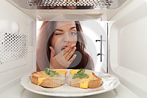 Girl looks in a microwave