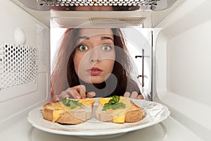 Girl looks in a microwave