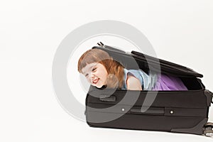 The girl looks out of the suitcase and laughs