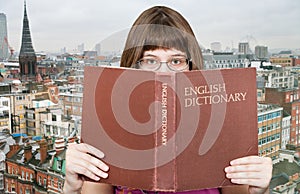 Girl looks over English Dictionary and skyline