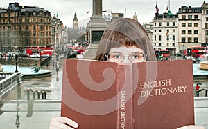 Girl looks over English Dictionary and square