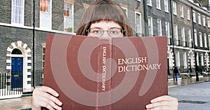 Girl looks over English Dictionary and street