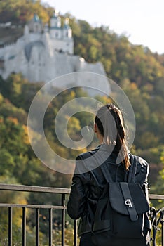 Girl looks at the park and the monastery. Young beautiful woman resting outdoor. Back view