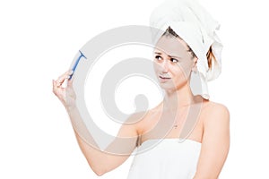 Girl looks at the razor with neglect on a white