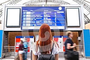 Girl looks on schedule on train station. Back view