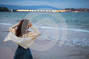 Girl looks at the sea and the city at sunset