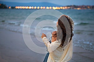 Girl looks at the sea and the city at sunset