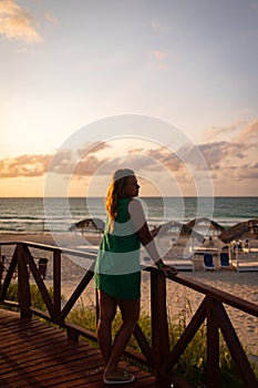 The girl looks at the sea at sunset