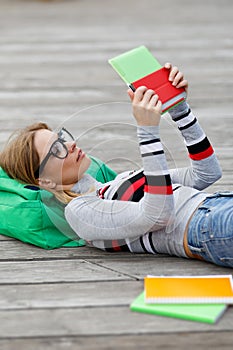 Girl looks at Tablet lying on wooden floor