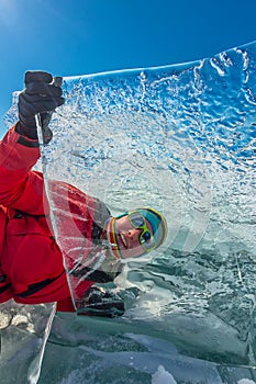 Girl looks through a transparent ice floe on the lake baikal