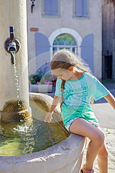 Girl looks at the water of old fountain on the typical square of small European villages, travel