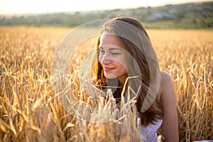 Girl looks at the wheat field at sunset