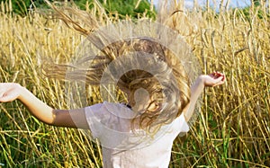 Girl with loose blond hair on the background of a wheat field on a summer farm. Summer, sun and warmth concept