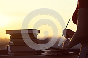 Girl with a lot of books on sunset background. Preparation for university exams. education concept