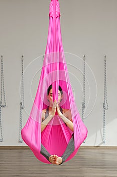 Girl lotus pose aerial antigravity yoga. Woman sits in hammock