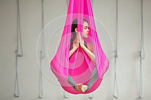 Girl lotus pose aerial antigravity yoga. Woman sits in hammock