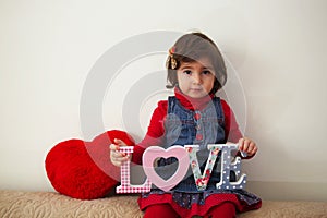 Girl with love sign and red plush heart