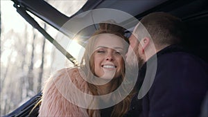 The girl lovingly looks at her husband. Beautiful couple in the woods. Girl with a guy sitting in the trunk of the car