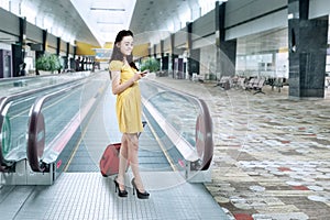 Girl with luggage and using cellphone in airport