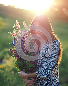 Girl with lupins in a dress at sunset