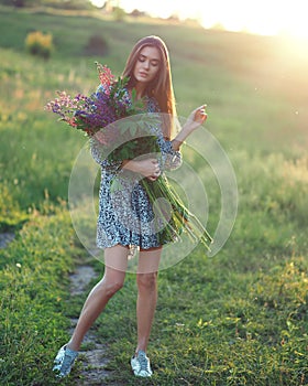 Girl with lupins in a dress at sunset