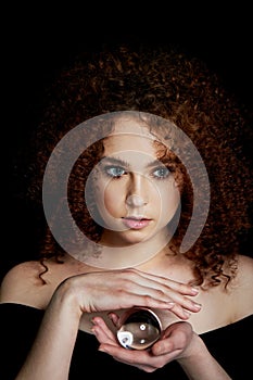 A girl with lush curly red hair. Holds in his hands a glass globe. Mystery,a premonition of the future.