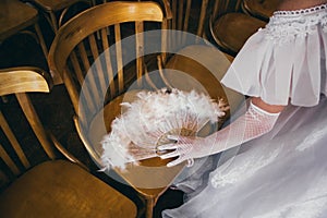 Girl in a lush white dress and in white gloves with beautiful hand fan