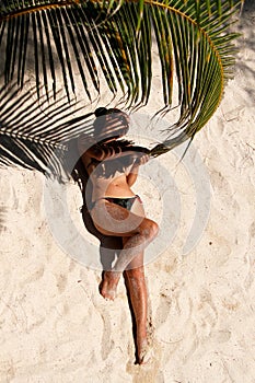 Girl lying on the beach and holding a palm branch.